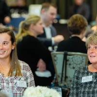 Kim Schmidt sitting with a student at Scholarship Dinner 2019